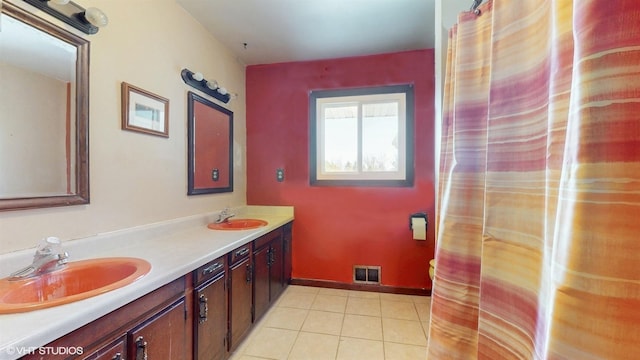 bathroom featuring a sink, visible vents, baseboards, tile patterned floors, and double vanity