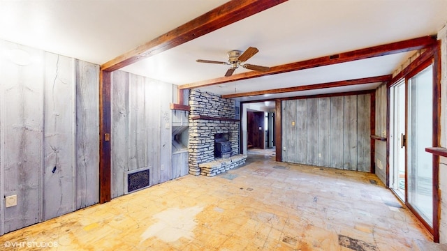 unfurnished living room featuring a fireplace, visible vents, a ceiling fan, wooden walls, and beamed ceiling