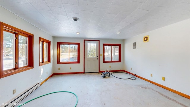 unfurnished room featuring a wealth of natural light, a baseboard radiator, baseboards, and unfinished concrete floors