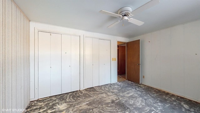 unfurnished bedroom with ceiling fan and two closets