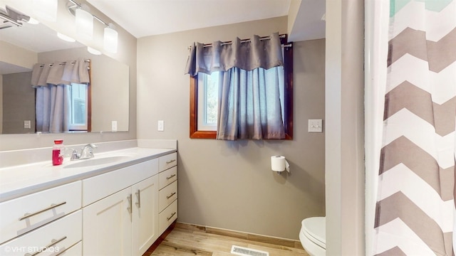 bathroom with toilet, visible vents, wood finished floors, and vanity