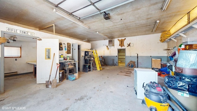 garage featuring a garage door opener, a baseboard heating unit, and a workshop area