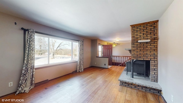 living room featuring wood-type flooring, a ceiling fan, and a brick fireplace