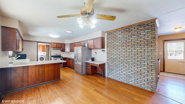 kitchen with stainless steel appliances, washer / clothes dryer, a peninsula, light wood-type flooring, and under cabinet range hood