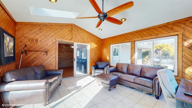 living area with light tile patterned floors, visible vents, lofted ceiling, ceiling fan, and wood walls