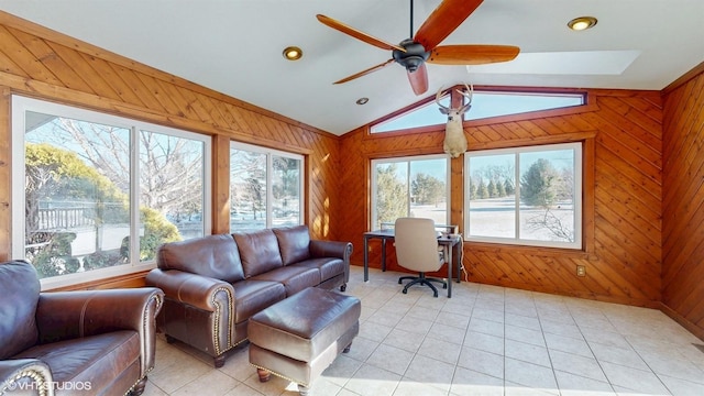 interior space with vaulted ceiling, light tile patterned floors, a ceiling fan, and wooden walls