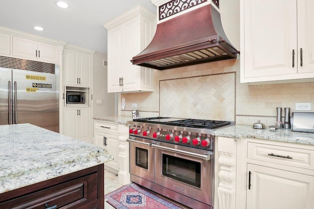 11735 Orchard St, Willow Springs, IL 60480 - kitchen featuring white cabinets, light stone counters, built in appliances, tasteful backsplash, and custom exhaust hood