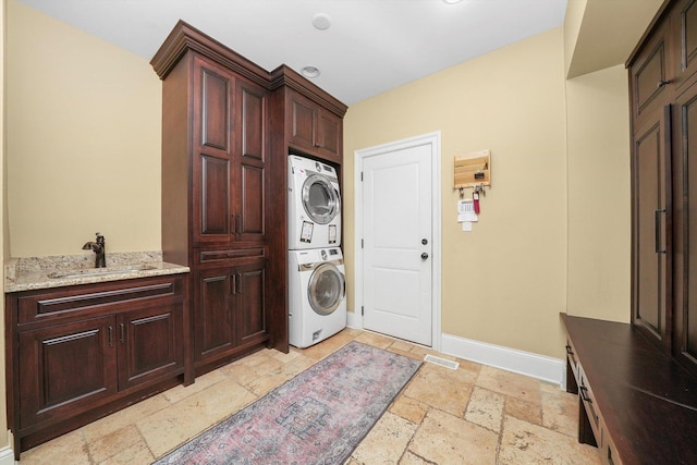 11735 Orchard St, Willow Springs, IL 60480 - washroom with a sink, stone tile floors, baseboards, cabinet space, and stacked washing maching and dryer