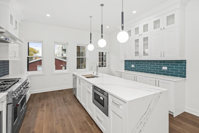 kitchen featuring a kitchen island with sink, a sink, white cabinets, appliances with stainless steel finishes, and dark wood-style floors