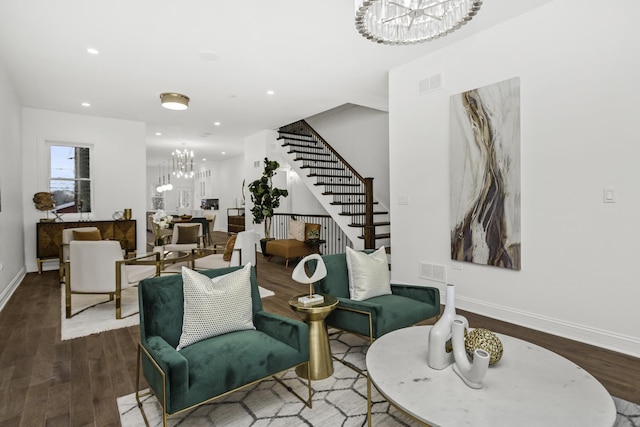 living area with a chandelier, visible vents, stairway, and wood finished floors