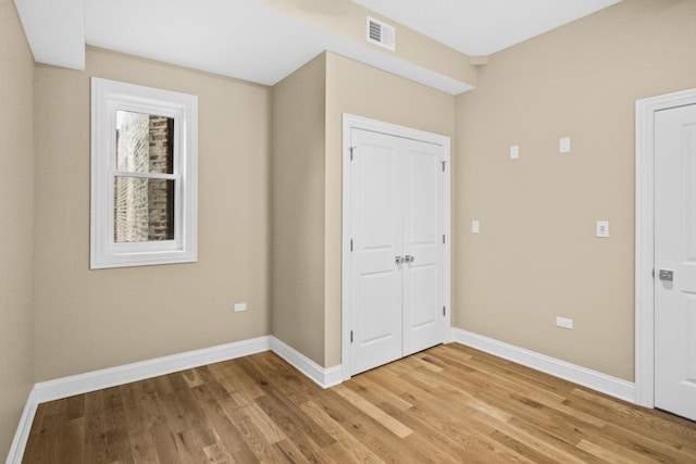 unfurnished bedroom featuring baseboards, a closet, visible vents, and light wood-style floors