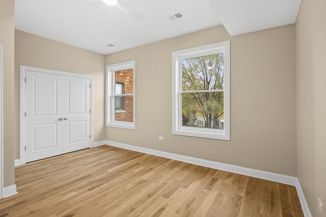 unfurnished bedroom with light wood finished floors, a ceiling fan, visible vents, and baseboards