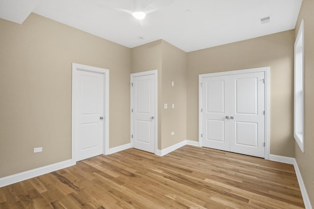 unfurnished bedroom with light wood-style floors, visible vents, ceiling fan, and baseboards