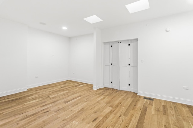 spare room with light wood finished floors, a skylight, baseboards, visible vents, and recessed lighting