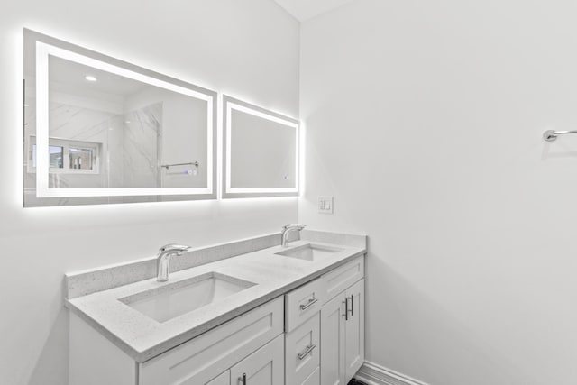 full bathroom featuring double vanity, baseboards, and a sink