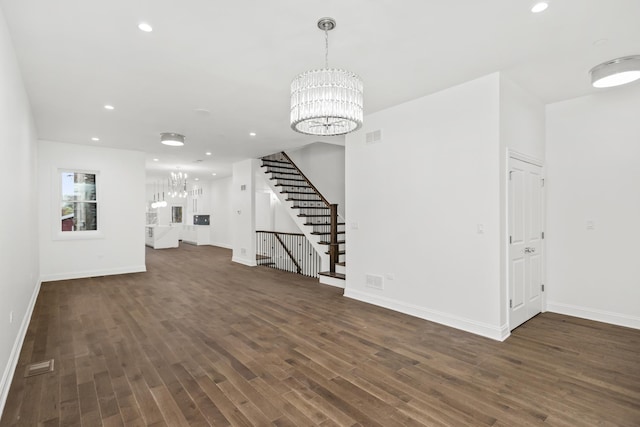 unfurnished living room with dark wood-type flooring, recessed lighting, stairs, and an inviting chandelier