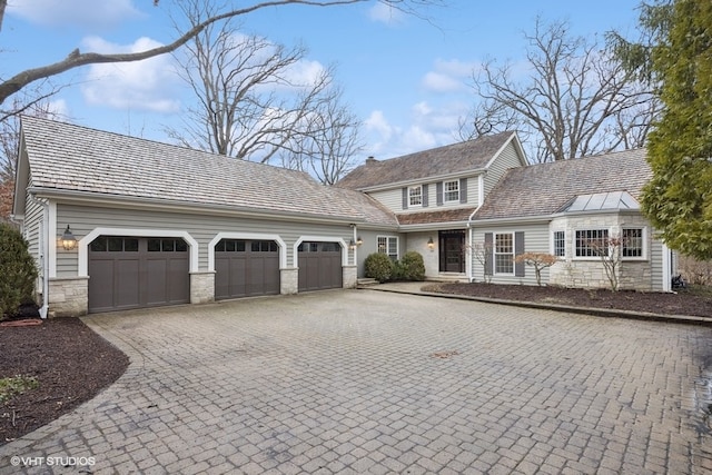 view of front of property featuring decorative driveway, stone siding, and a garage