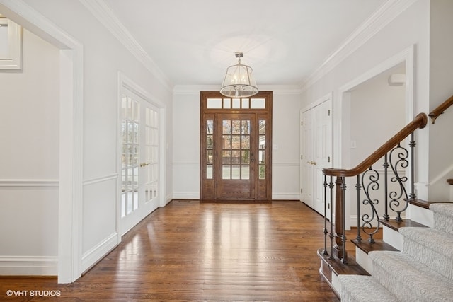 entrance foyer featuring ornamental molding, stairway, an inviting chandelier, and wood finished floors