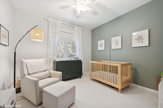 bedroom with a crib, carpet, baseboards, and a ceiling fan