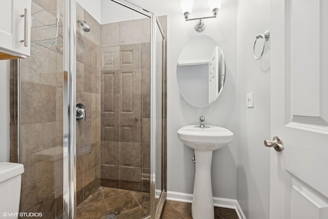 full bath with tile patterned flooring, a stall shower, toilet, and baseboards