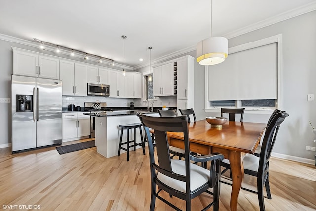 dining area with baseboards, light wood finished floors, and ornamental molding