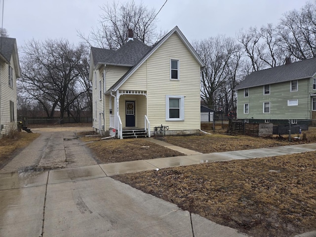 view of front of property with driveway, roof with shingles, and fence