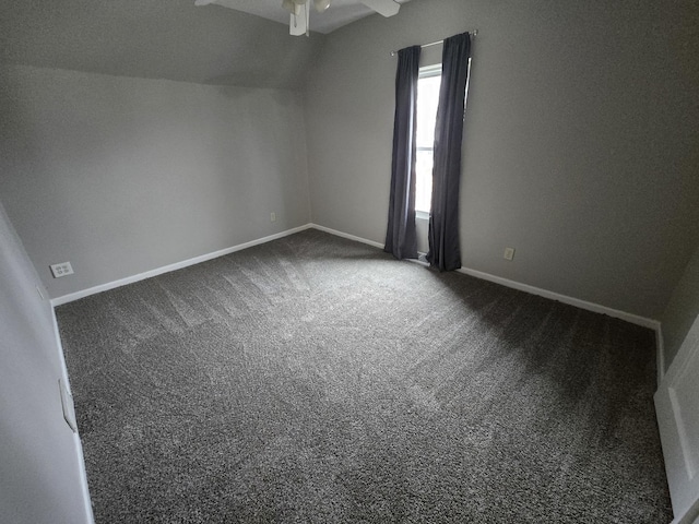 additional living space with baseboards, dark carpet, vaulted ceiling, and a ceiling fan