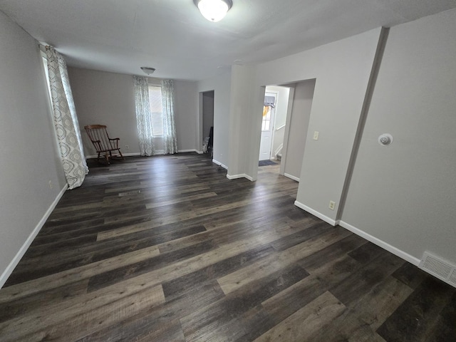 empty room featuring baseboards, visible vents, and dark wood finished floors