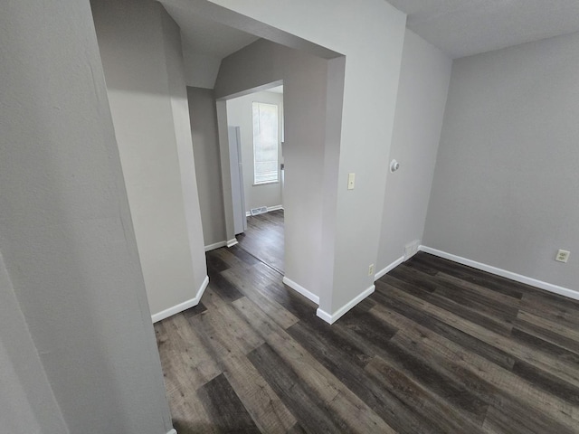 hallway with dark wood-type flooring and baseboards