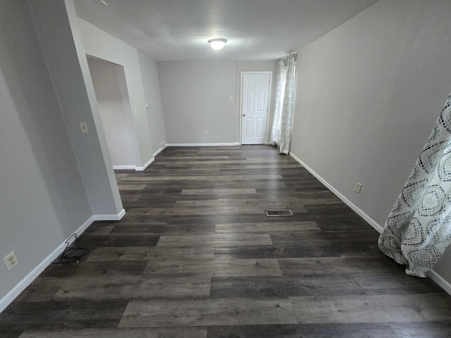 spare room featuring dark wood-style floors, visible vents, and baseboards