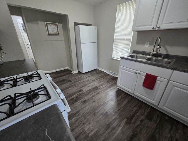 kitchen with white appliances, visible vents, white cabinets, dark wood-type flooring, and a sink