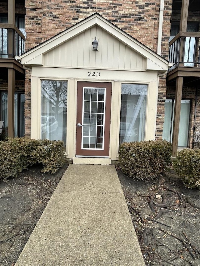 entrance to property with board and batten siding, brick siding, and a balcony