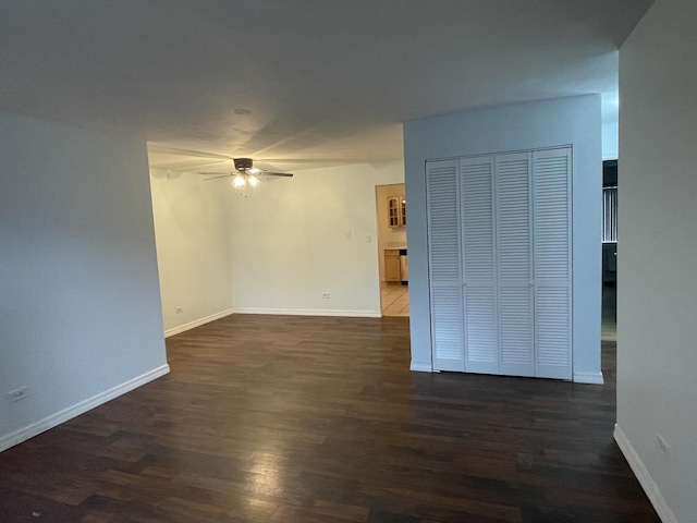 spare room featuring ceiling fan, dark wood-style floors, and baseboards