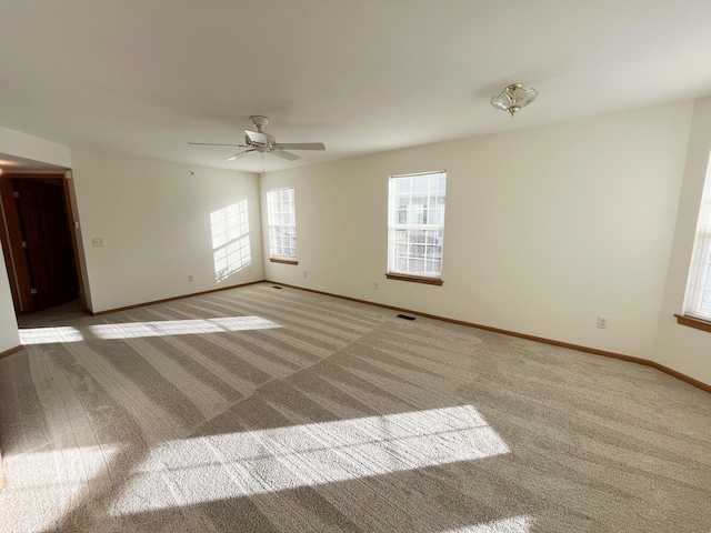 spare room featuring a ceiling fan, baseboards, visible vents, and carpet flooring