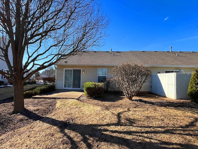 rear view of house featuring a patio area, fence, and roof with shingles