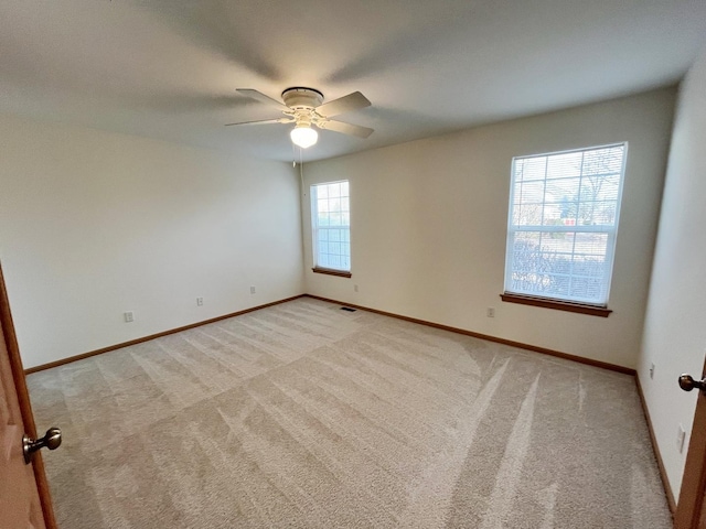 empty room featuring light carpet, baseboards, visible vents, and a ceiling fan