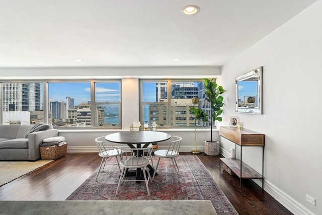 dining area with baseboards, recessed lighting, wood finished floors, and a city view