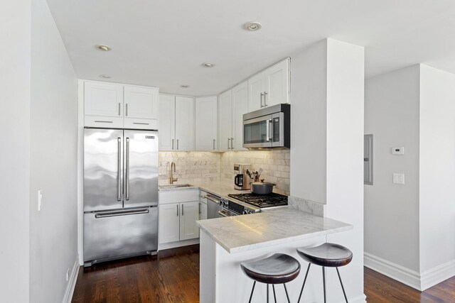 kitchen with white cabinetry, appliances with stainless steel finishes, decorative backsplash, and dark wood finished floors