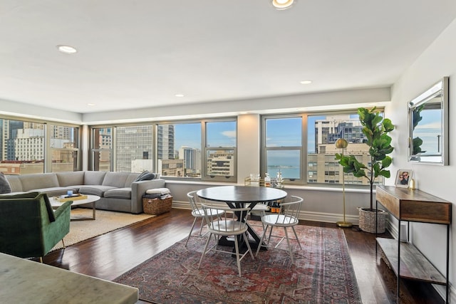 dining room featuring a view of city, recessed lighting, wood finished floors, and baseboards