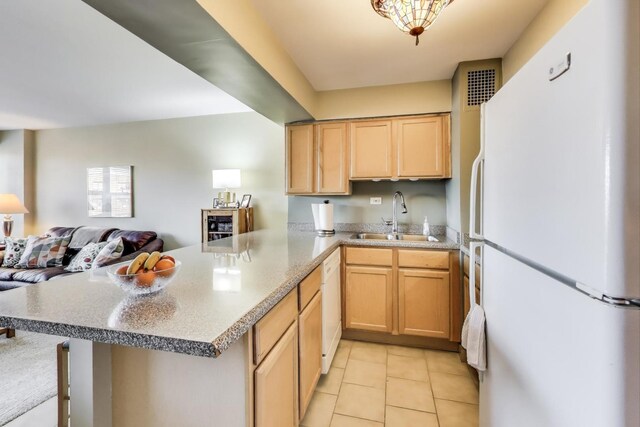 kitchen with open floor plan, a peninsula, light tile patterned flooring, white appliances, and a sink
