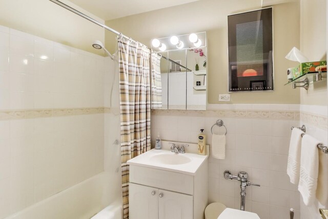 bathroom with vanity, tile walls, shower / tub combo, and toilet