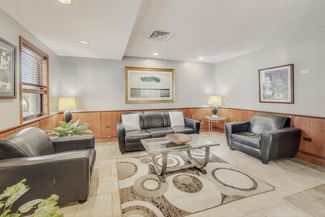 living room featuring recessed lighting, visible vents, wood walls, and wainscoting