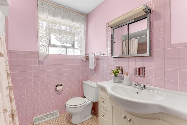 bathroom featuring tile patterned flooring, visible vents, toilet, and tile walls