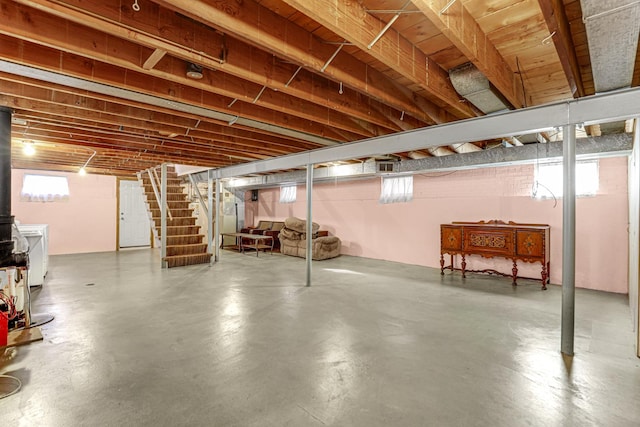 basement with a wealth of natural light, stairway, and a wood stove