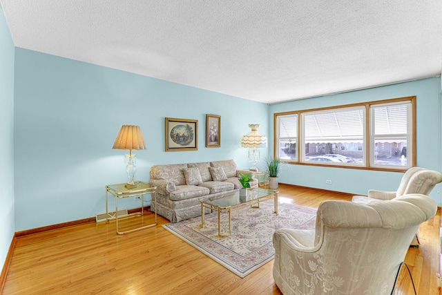 living room with visible vents, a textured ceiling, baseboards, and wood finished floors