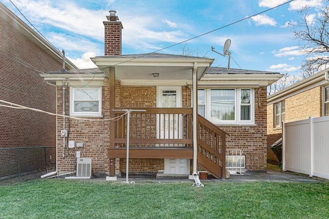 rear view of house with brick siding, a yard, and fence