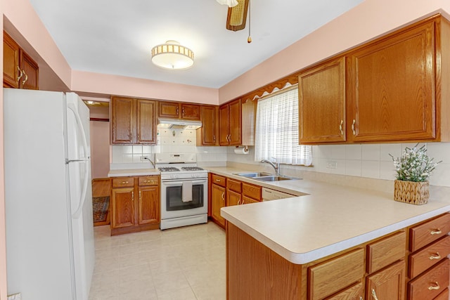 kitchen with under cabinet range hood, light countertops, brown cabinetry, white appliances, and a sink