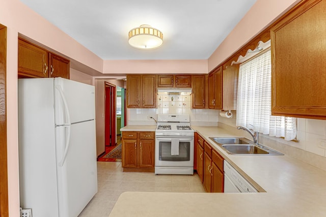 kitchen featuring a sink, white appliances, brown cabinetry, and light countertops