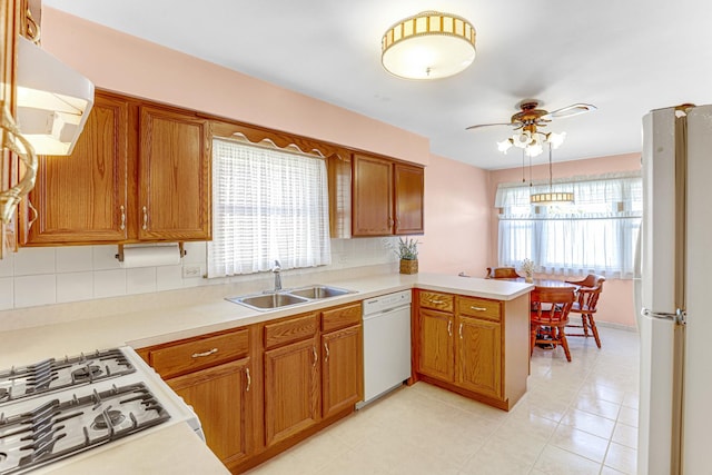 kitchen with a sink, white appliances, a peninsula, and light countertops