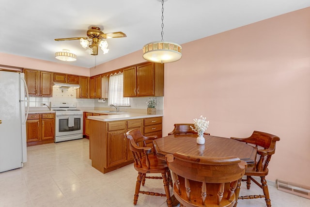 kitchen with visible vents, under cabinet range hood, a peninsula, white appliances, and a sink